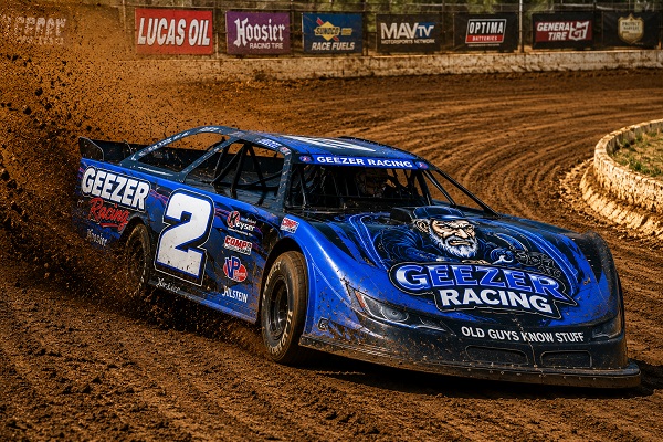 Grumpy Old Geezer Racing dirt-track car sliding sideways through a dirt oval corner
